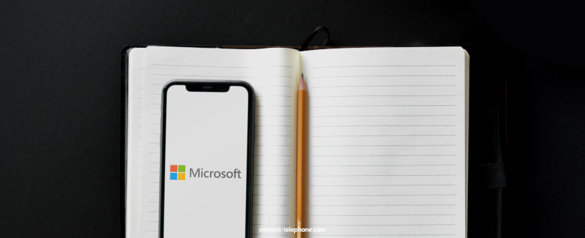 Téléphone, affichant le logo de Microsoft, posé sur un carnet à côté d'un crayon.