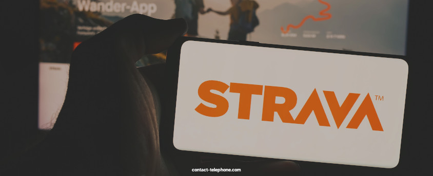 Smartphone affichant le logo de Strava devant un écran d'ordinateur sur le quel le site internet de Strava est affiché.